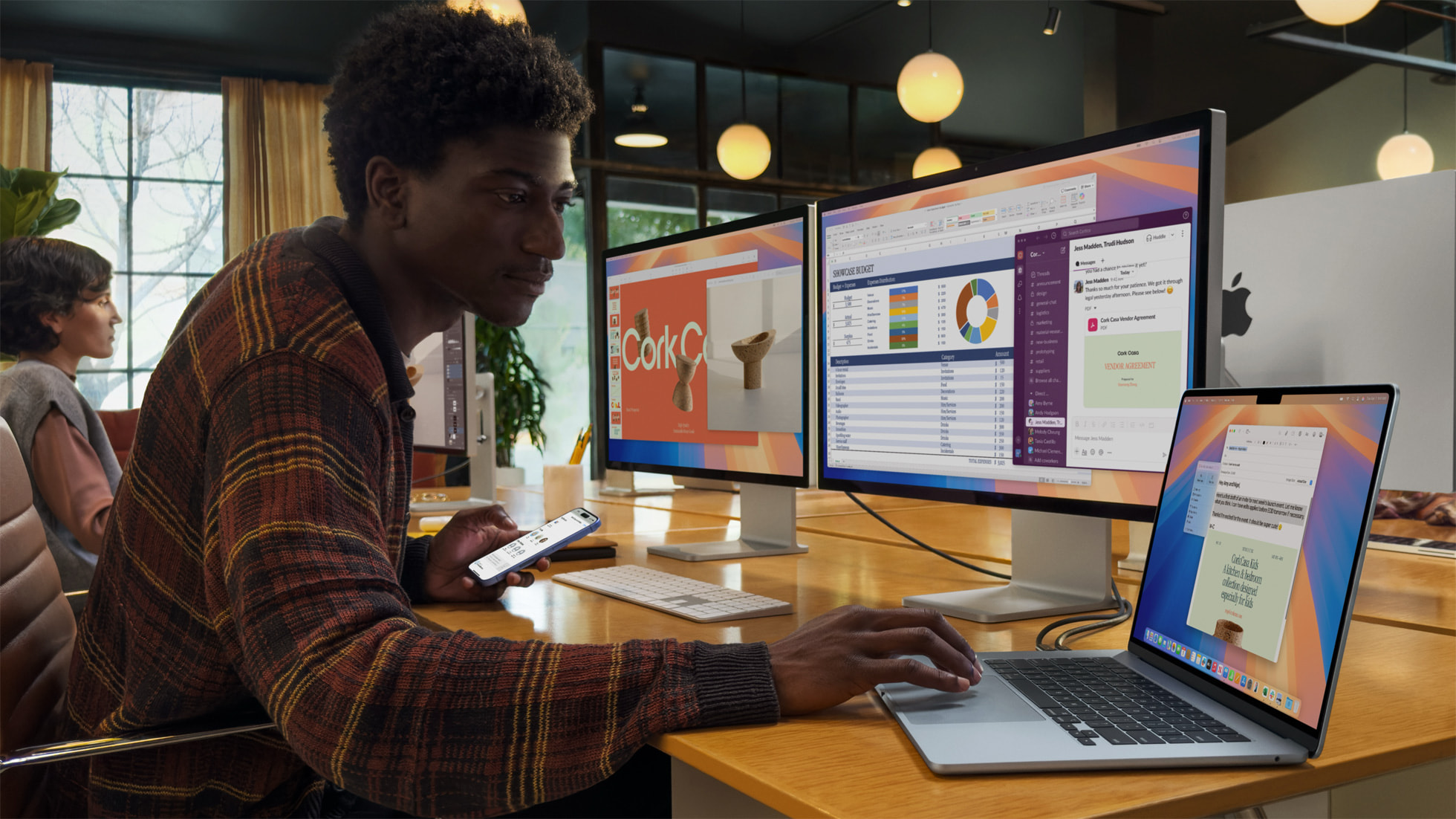 A man uses a MacBook Air aong with two external monitorrs.