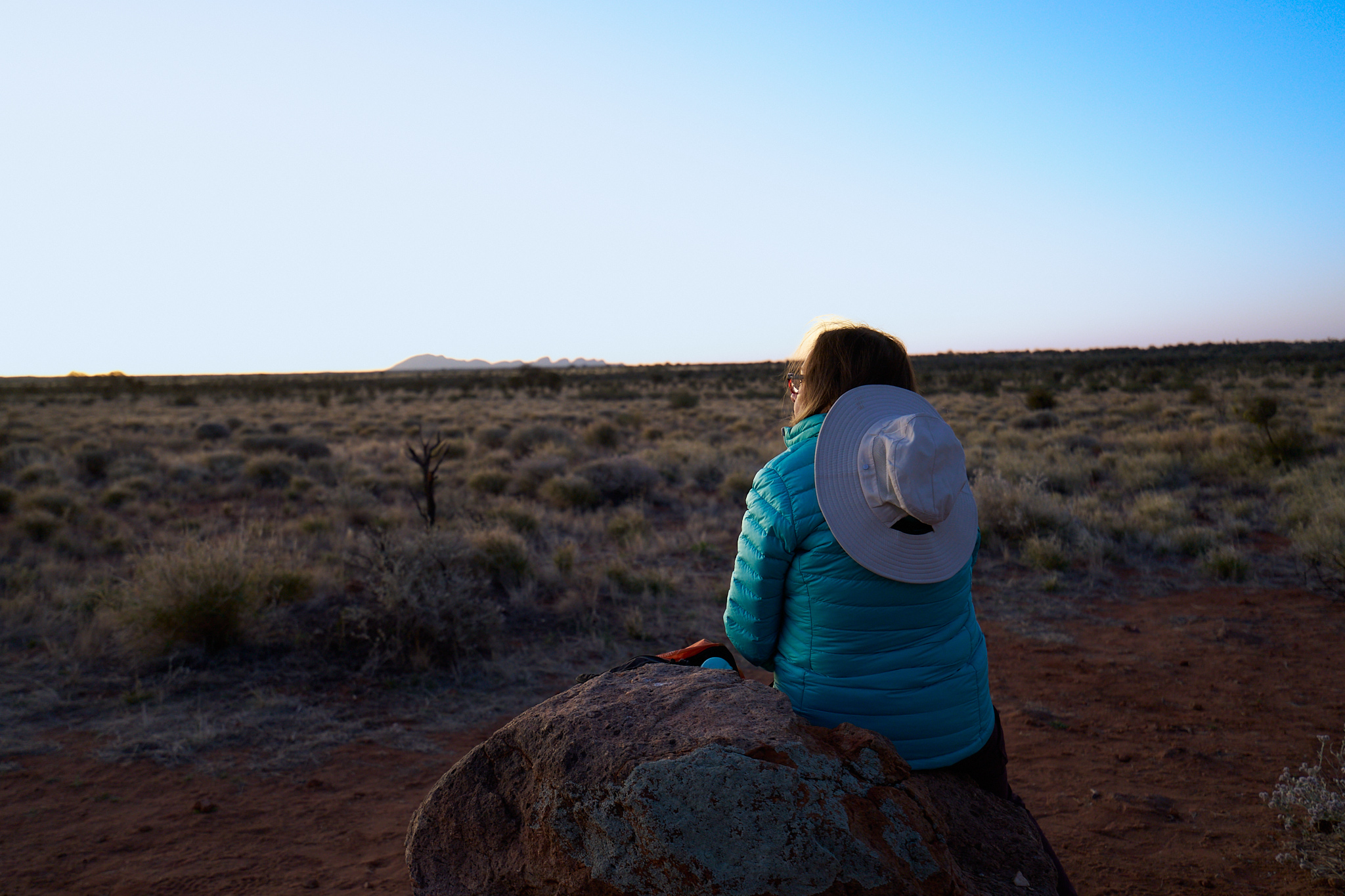 A woman watches sunset in the outback.